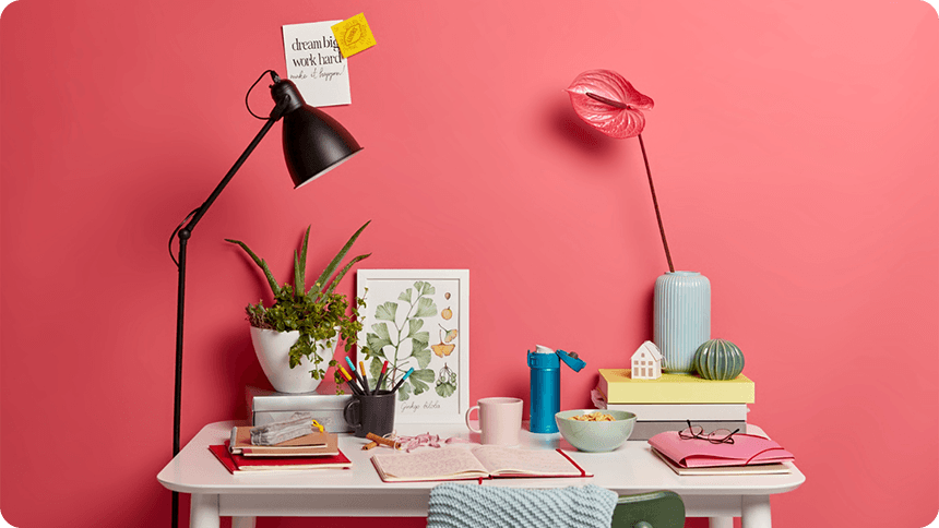 壁に向かった机にお花屋飲み物と一緒にノートが開かれている部屋の一部