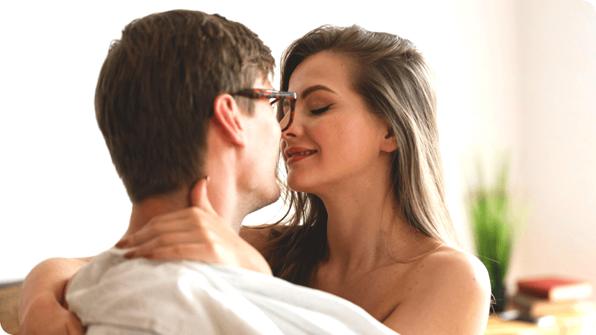 男女で向かい合って座り、女性が男性に首に腕を回し、顔を近づけている