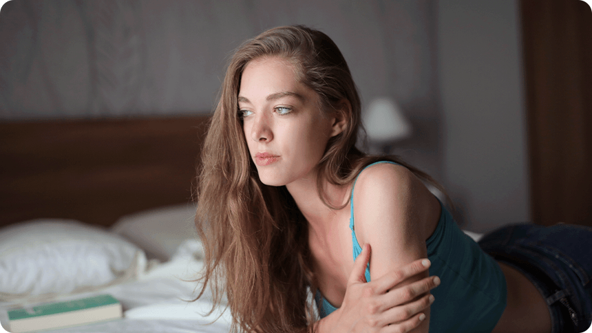 ベッドの上で物思いにふける女性。恋愛や関係について静かに考える姿。