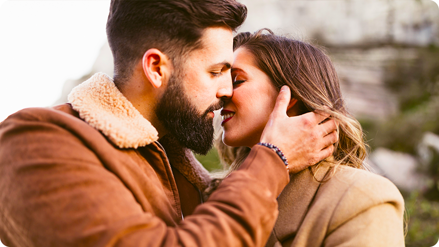 男性が女性の顔に手をやさしく添えながら、キスをしようとしているカップル