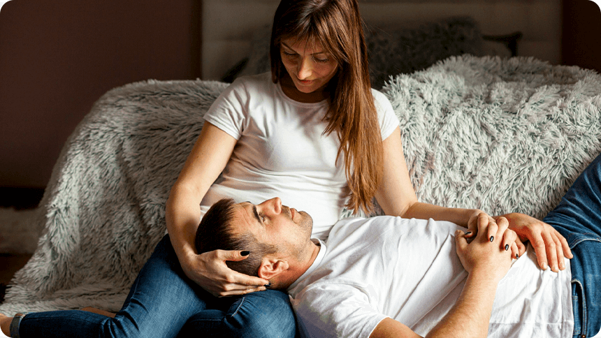 寝室で男性が彼女の腿に頭をのせ穏やかな時間を過ごす様子