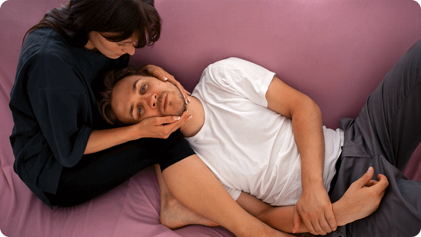 ソファーで男性が力なく女性にもたれかかる様子