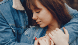 パートナーに抱きしめられながら、静かに目を閉じて寄り添う女性