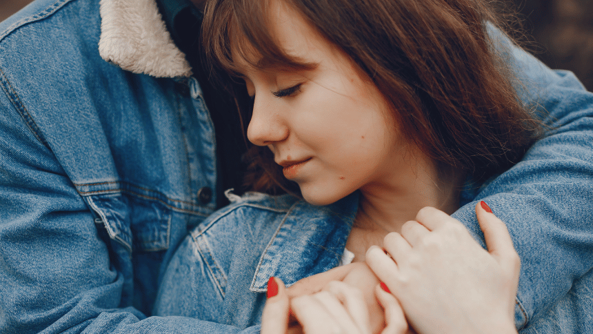 パートナーに抱きしめられながら、静かに目を閉じて寄り添う女性